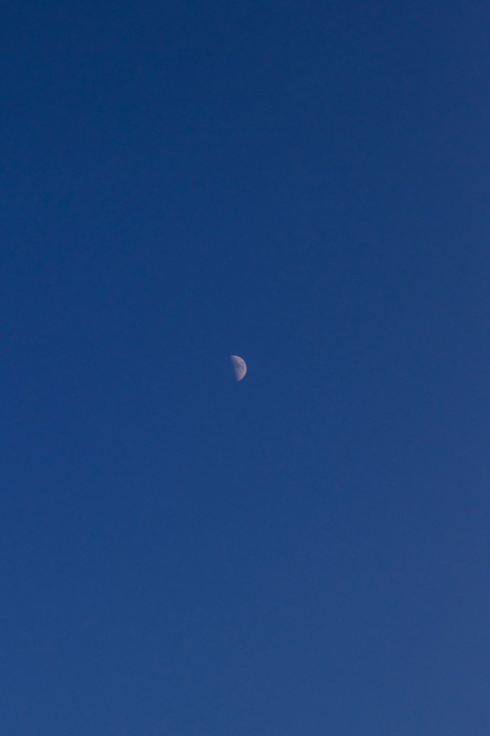 Una luna creciente fina en lo alto de un cielo azul profundo sobre Formentera.