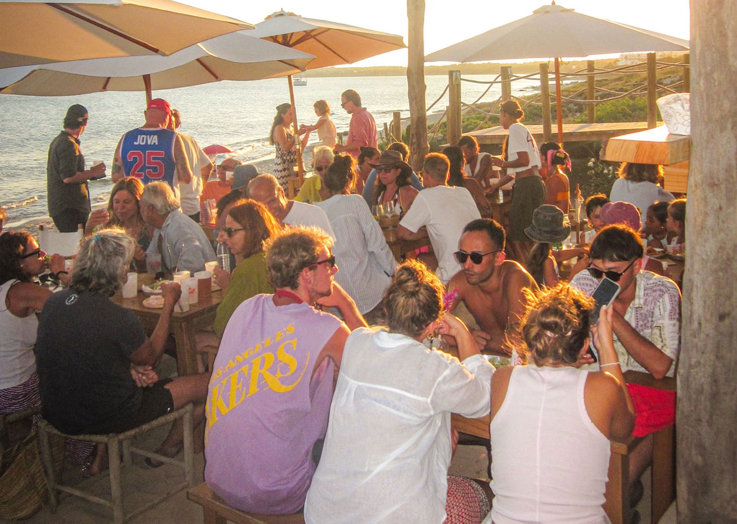 Invitados apretados en las mesas de AMAR a última hora de la tarde, con el mar justo detrás.